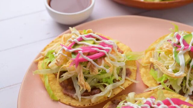 Aerial view of traditional Mexican chicken tostadas with refried beans, lettuce, cheese and avocado