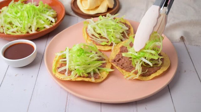 Preparing a Mexican tostada with lettuce. Traditional Mexican food