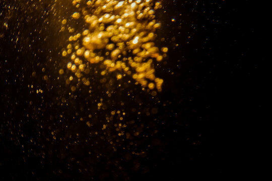 Abstract blurred golden bokeh lights against a dark background, creating a dramatic and festive atmosphere with glowing and shimmering effects, perfect for holiday and celebration themes.