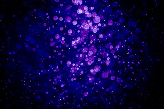 Blurred photo with purple violet and blue dots visible glittering, shining brightly look and feel luxurious