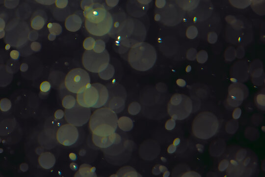 Defocused bokeh lights in various sizes and colors on a dark background creating a dreamy and abstract visual effect