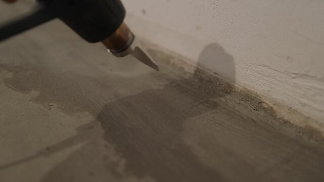 Close-up of a heat gun being used to speed up the drying of freshly applied filler on a wall. A DIY repair and renovation detail &ndash; note that forced heat can cause the filler to crack.