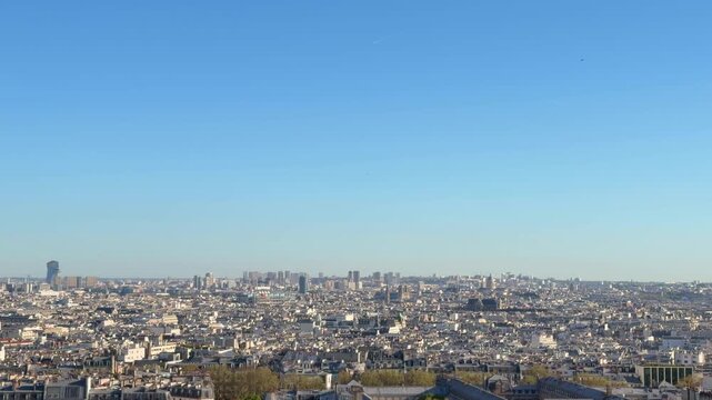 Breathtaking panoramic view of the Paris cityscape from an elevated perspective, showcasing the dense urban architecture and rooftops stretching to the horizon under a clear blue sky