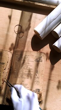 Close-up overhead footage of a preservation expert examining delicate pages of an antique storybook. Ideal for themes of historical research, archival discovery, and cultural preservation.