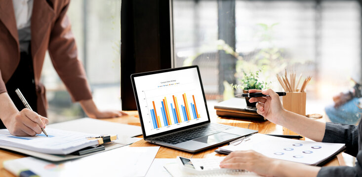 Close up of business people analyzing financial charts on laptop in office
