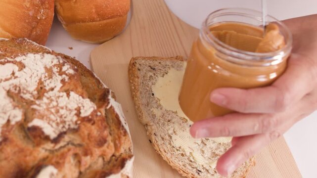 Spreading Creamy Peanut Butter on Multigrain Bread with Assorted Bakery Loaves