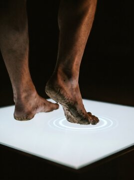 Dirty barefoot stepping on glowing digital panel representing nature meeting modern technology