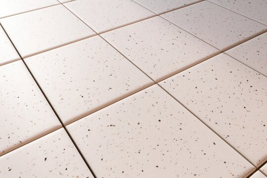 Close-up view of beige ceramic tiles with a speckled pattern arranged in a grid on a flat surface.