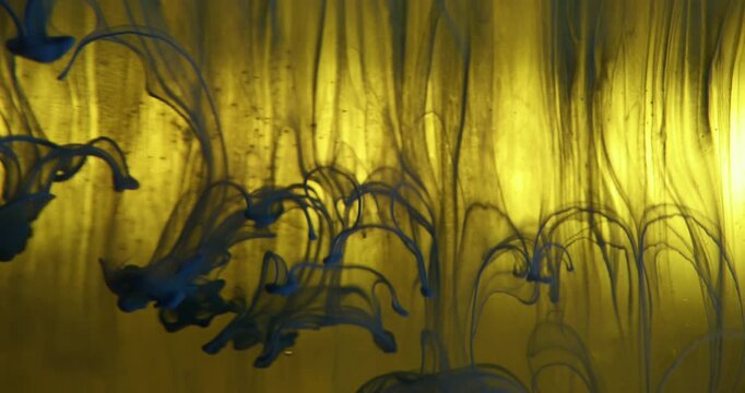 Acrylic fluid. Paint liquid. Defocused yellow blue colorful wet particles drip smoke pigment in water wave on abstract art background.