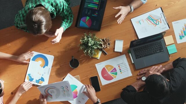 Top view of project manager using tablet to analyze data and financial chart while marketing team working together to brainstorm marketing campaign or planning strategy at meeting room. Convocation.