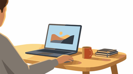 Fototapeta premium A person sits at a wooden desk with a laptop displaying a landscape and a cup of coffee