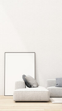 Minimalist neutral living room with a textured grey sectional, layered cushions and blank framed poster against a white textured wall.