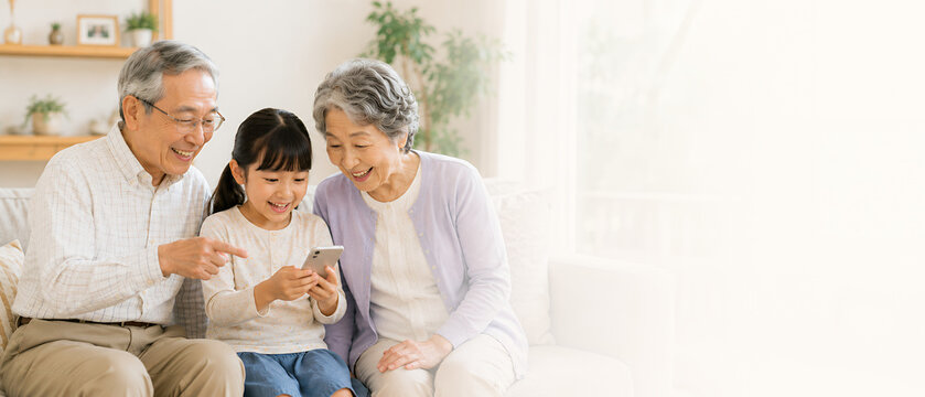 スマートフォンを一緒に見る祖父母と孫の家族風景