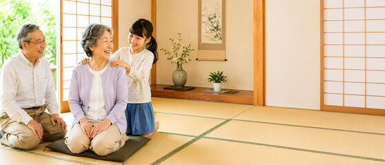 敬老の日に肩たたきをする孫と祖父母の家族風景