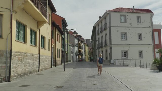 Tourist Walking Through Historic Streets of Luanco, Asturias, Spain Summer Travel Destination