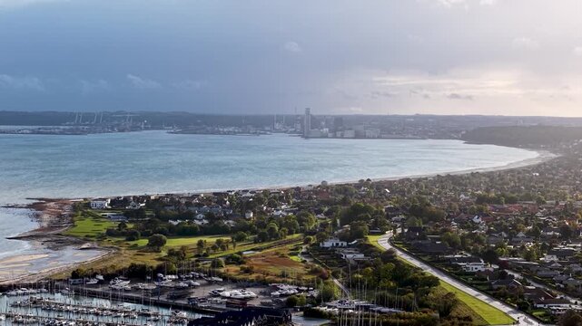 Aerial drone view of Aarhus Bay and Egaa Marina stretching along the scenic Danish coastline under dramatic skies
