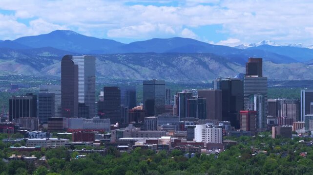 City of Denver Front Range snow-capped Rocky Mountains landscape Mile High skyscraper skyline cityscape buildings downtown Denver Colorado drone aerial Spring morning blue sky cloudy backwards up