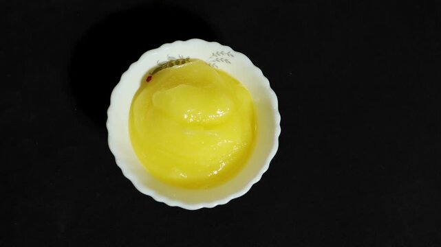 pure desi ghee in white bowl isolated on black background