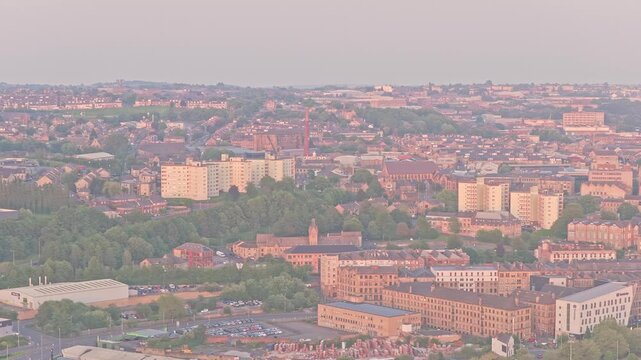Residential districts, industrial heritage and urban green spaces in Bradford, West Yorkshire, England, unfold beneath warm evening light with a prominent textile-industry chimney visible in skyline