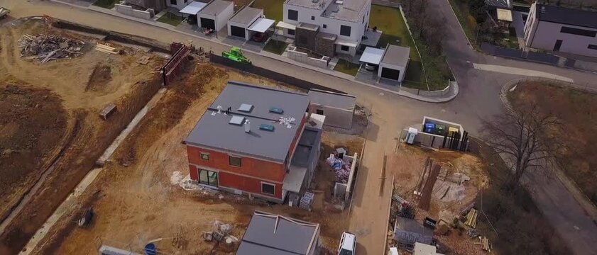 Green machinery drives past new houses under active construction