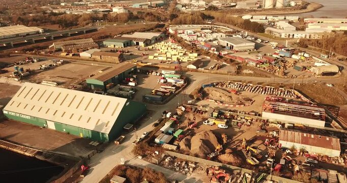 Aerial view of the Port of Cardiff industrial area featuring warehouses, shipping containers, and stockpiles of materials along the waterfront in Cardiff, Wales, United Kingdom.