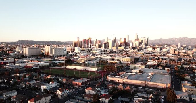 Aerial view of the Los Angeles skyline during golden hour with urban sprawl and distant mountains in Los Angeles, California, United States.