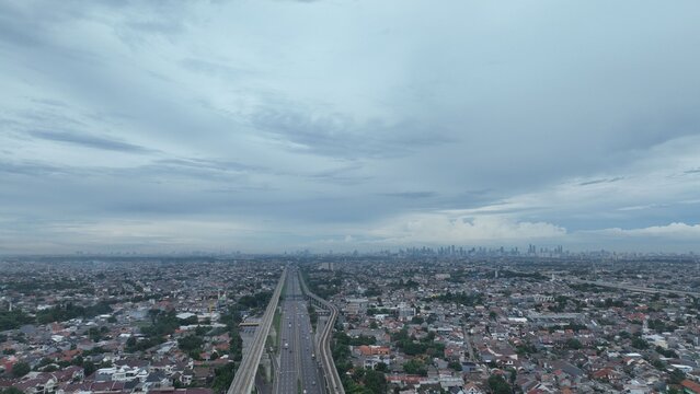 Aerial view of the highway and railway infrastructure cutting through the dense urban landscape of Bekasi Barat, West Java, Indonesia.