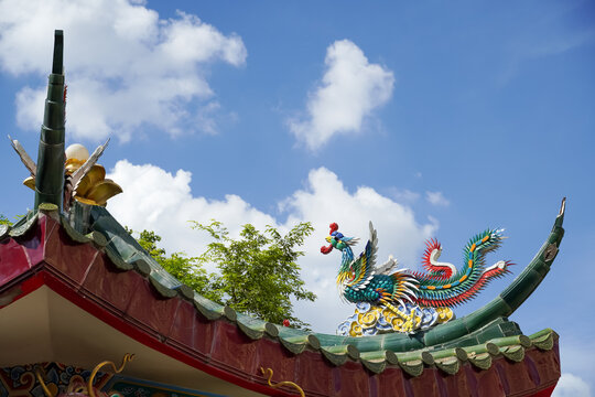 Colorful phoenix statue adorns the ornate roof of a traditional Asian temple