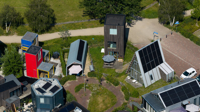 Aerial view of unique modern tiny homes with solar panels and diverse architectural designs in a residential neighborhood in Almere, Flevoland, Netherlands.