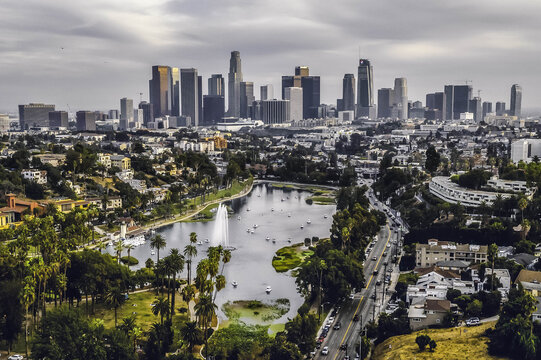 Aerial view of Echo Park Lake with its fountain and swan boats, surrounded by parkland, set against the Los Angeles skyline. Los Angeles, California, United States.
