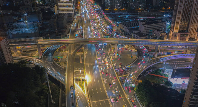 Aerial view of the illuminated Tianmu Road intersection at night, featuring multi-level highway overpasses with flowing traffic light trails in Shanghai, Shanghai, China.
