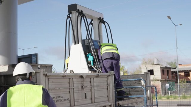 Workers loading and unloading a fuel dispenser for a gas station. Hydrocarbons, energy, transportation, logistics, oil industry