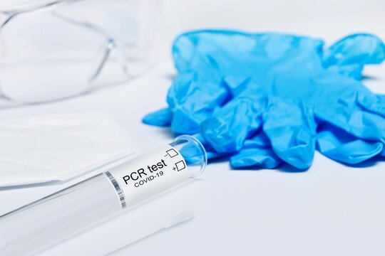 Covid-19 PCR test kit vial with blue nitrile gloves medical mask and safety goggles for pandemic advertising and healthcare website design.