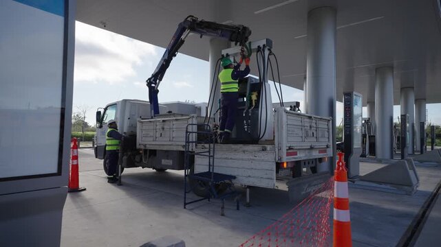 Workers loading and unloading a fuel dispenser for a gas station. Hydrocarbons, energy, transportation, logistics, oil industry