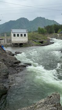 A view of the Chemal Hydroelectric Power Plant with a turbulent mountain river flowing past it in the Republic of Altai, Russia