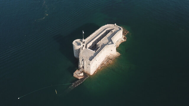 Aerial view of the historic stone fortress of Chateau du Taureau surrounded by deep blue sea waters in Plouezoc'h, Bretagne, France.
