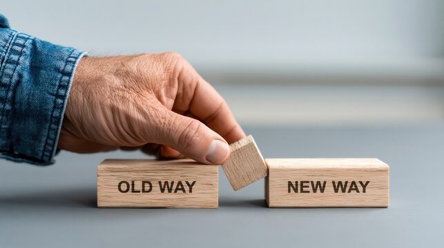 Businessman's hand moving a wooden block labeled "NEW WAY" to join another block, symbolizing a shift from old.old way vs new way
