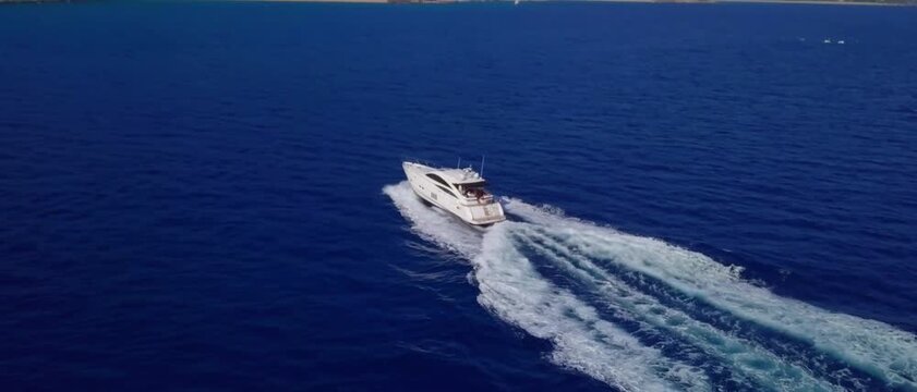 Luxury white yacht sails quickly across deep blue sea