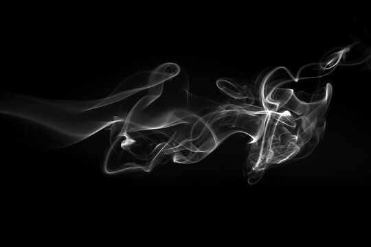 White smoke wisps and swirls isolated on a black background.