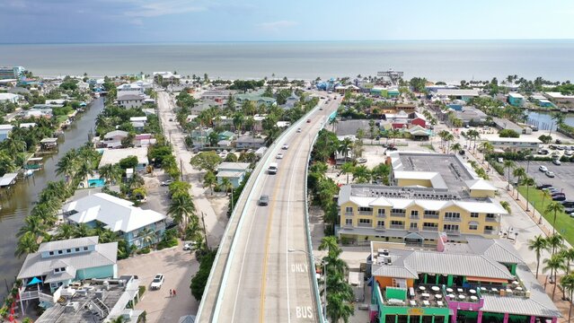 Aerial view of Matanzas Pass Bridge leading into the coastal town of Fort Myers Beach with colorful buildings and palm trees, Fort Myers, Florida, United States.