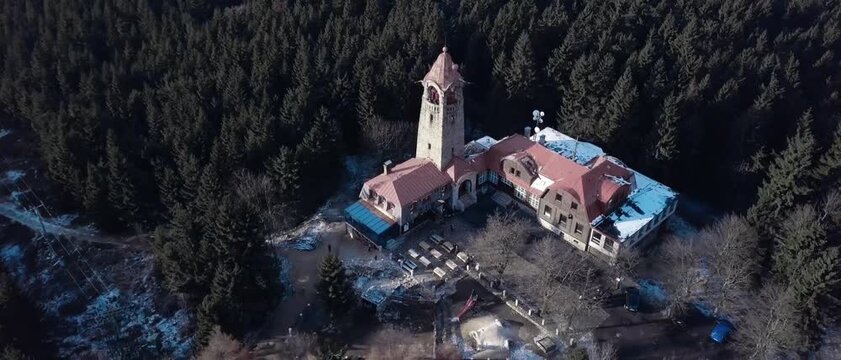 Circling above stone tower building among thick pine trees