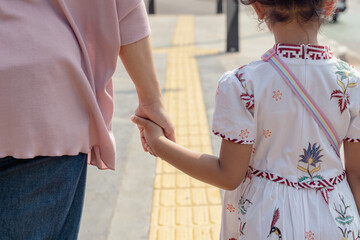 Obraz premium A mother and her little daughter walking together and holding hands
