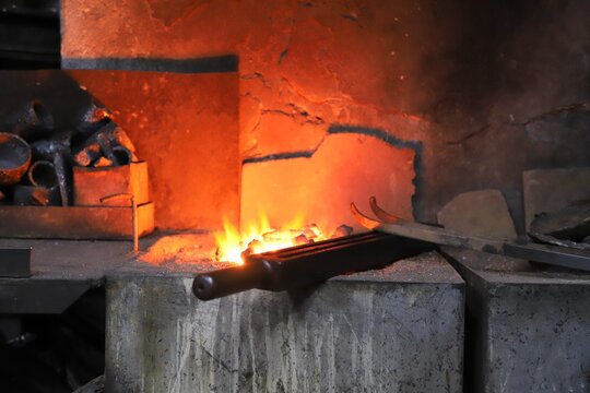The process of heating metal held with tongs in a traditional blacksmith&rsquo;s forge until it reaches a white-hot state over a coal fire