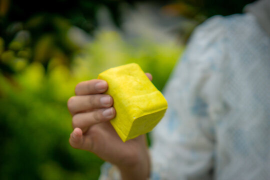 A young Asian Muslim woman enjoys tahu takwa (yellow tofu) in the garden. A typical dish from Kediri, Indonesia.