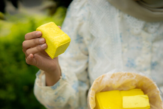A young Asian Muslim woman enjoys tahu takwa (yellow tofu) in the garden. A typical dish from Kediri, Indonesia.