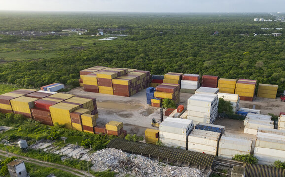 Aerial view of Puerto Progreso showing stacks of colorful shipping containers in a storage yard surrounded by lush green vegetation in Progreso, Yucatan, Mexico.