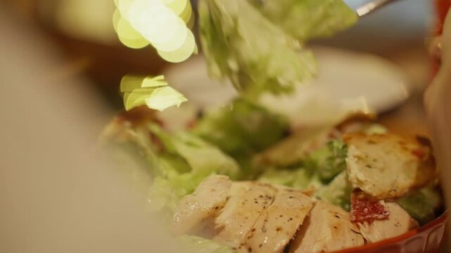 Person eating fresh chicken caesar salad with a fork