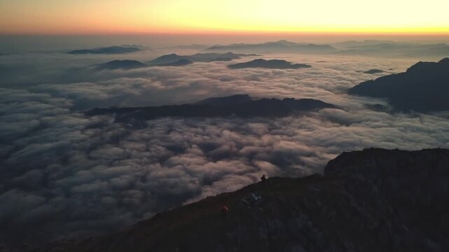 Vista a&eacute;rea del amanecer desde la cumbre de las monta&ntilde;as  con un mar de nubes de color dorado 