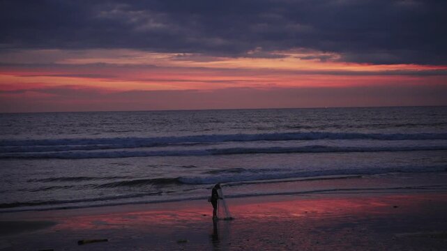 Fisherman casting fishing net at sunset on the beach