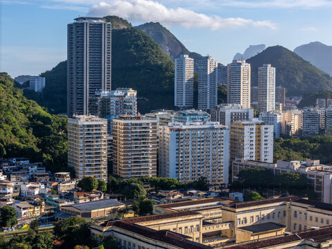 Aerial view of Botafogo neighborhood featuring high-rise residential buildings nestled against lush green mountains under a clear sky, Rio de Janeiro, Rio de Janeiro, Brazil.